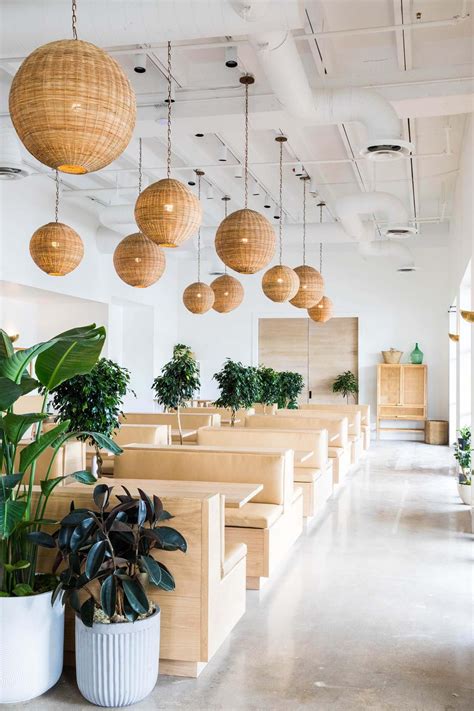the interior of a restaurant with wooden tables and planters hanging
