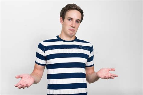 Portrait Of Young Man Shrugging Shoulders And Looking Confused Stock