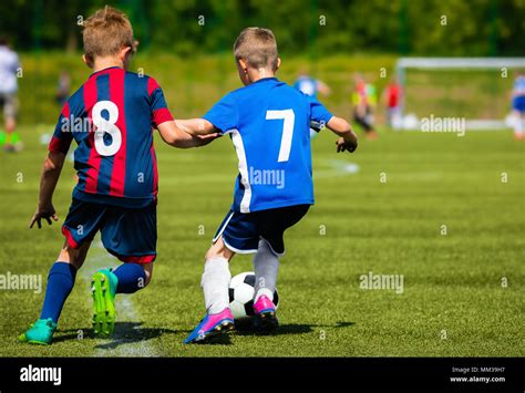 Two Young Soccer Players Kicking Soccer Ball On Grass Pitch Youth