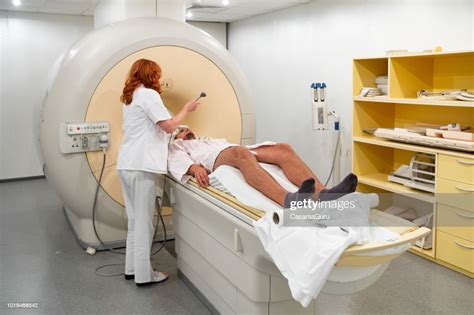 Female Doctor Preparing Young Male Patient For Magnetic Resonance