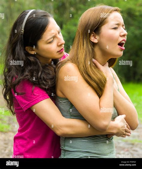 Young Woman Choking With Lady Standing Behind Performing Heimlich Maneuver Park Environment And