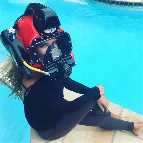 A Woman Sitting On The Edge Of A Swimming Pool Wearing A Diving Helmet And Goggles