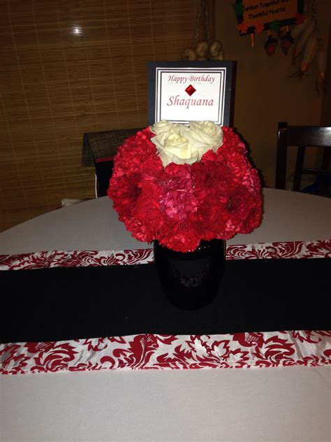 Red And White Flowers In A Black Vase On A Table With A Name Card
