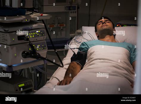 Patient Lying In Bed Attached To Monitoring Equipment In Intensive