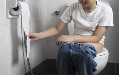 Asian Boy Sitting On Toilet Bowl Holding Tissue Paper Health Problem Concept Stock