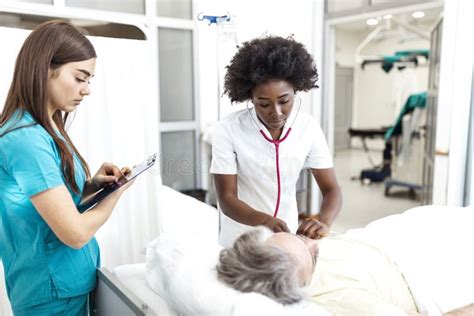 female doctor and nurse talking to male patient in hospital bed african american doctor with