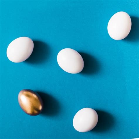 Free Photo Overhead View Of Golden Egg Among The White Eggs On Blue