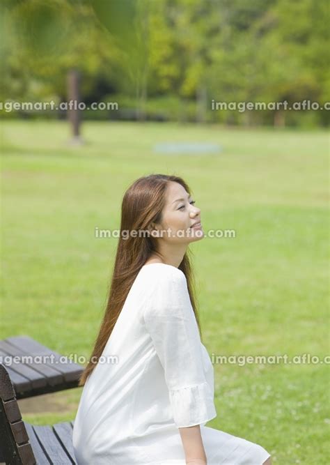 公園のベンチに座る若い女性の写真素材 12708364 イメージマート