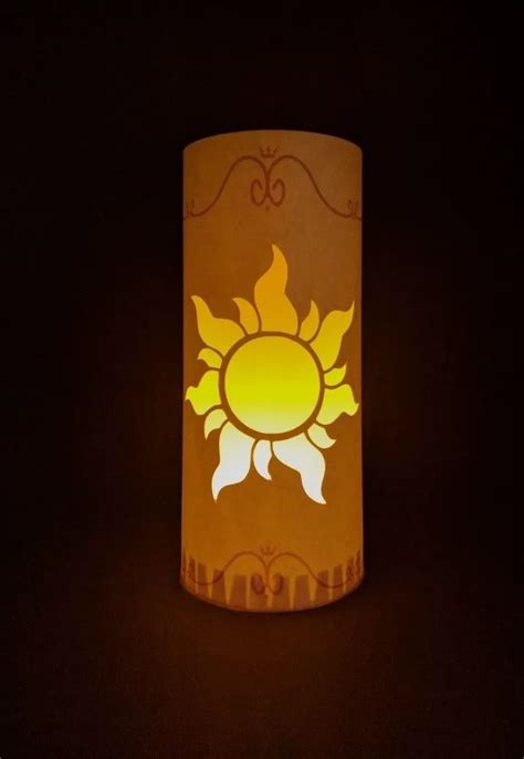 A Lit Candle With The Shape Of A Sun On Its Side In The Dark