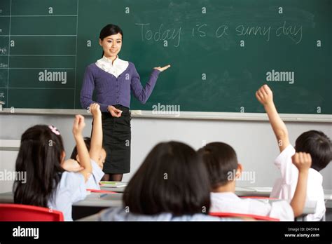 Teacher Standing By Blackboard In Chinese School Classroom Stock Photo