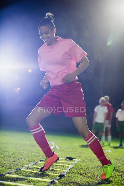 Young Female Soccer Players Practicing Agility Sports Drill On Field At