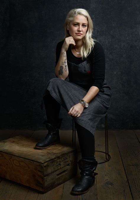 A Woman Sitting On Top Of A Wooden Box In Front Of A Black Wall With