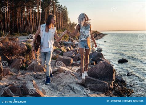 Caring Man Holding Hand Of His Girlfriend While Walking Along The Rocky