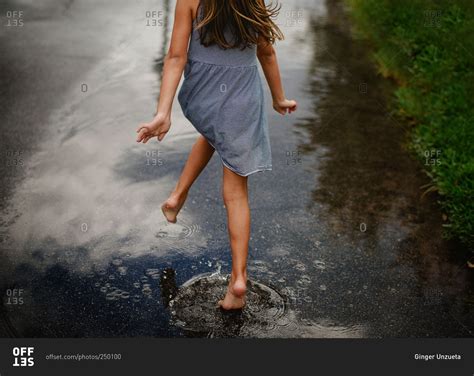 Girl Running Barefoot Through A Puddle On The Street Stock Photo OFFSET