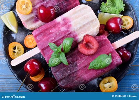 fruit and berry popsicles on the plate with ice pieces of kumquat lime and cherries and mint