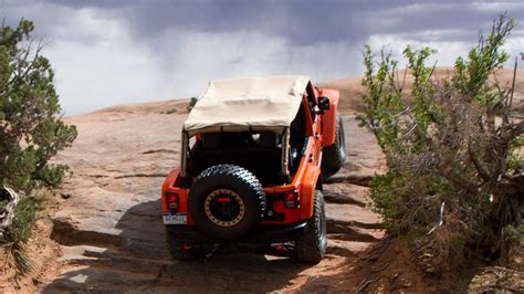 An Orange Jeep Driving Down A Dirt Road