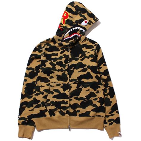 Founded by nigo in 1993, a bathing ape® emerged from its underground harajuku beginnings to become one of the most iconic streetwear symbols in the world, with their signature designs including the ape head, bape® camo, bape sta™, shark hoodie. BAPE 1ST CAMO SHARK PONR ZIP HOODIE YELLOW | PREMIUMSWAG