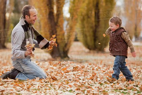 Caucasian Father And Son Playing In Autumn Leaves Stock Photo Dissolve