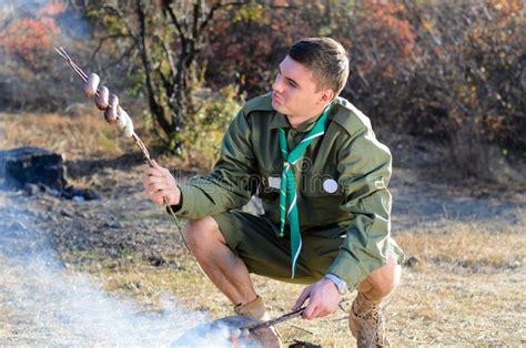 Boy Scout Cooking Sausages En Los Palillos Sobre Hoguera Foto De