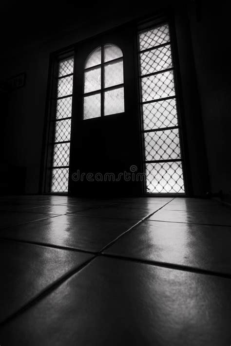 Windows And A Door In A Dark Room With Light Streaming Onto Tiled Floor