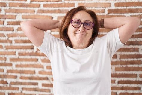 Senior Woman With Glasses Standing Over Bricks Wall Relaxing And