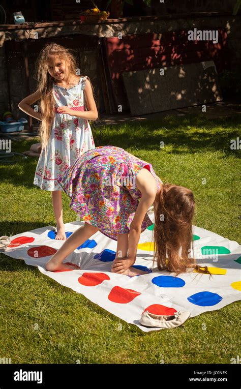 Two Little Sisters Playing Twister Game At Yard On Grass Stock Photo