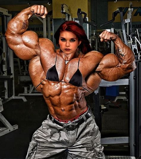 A Female Bodybuilt Posing For A Photo In The Gym With Her Muscles
