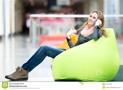 Smiling Female Sitting In Bean Bag In Office Or Shopping Center Stock
