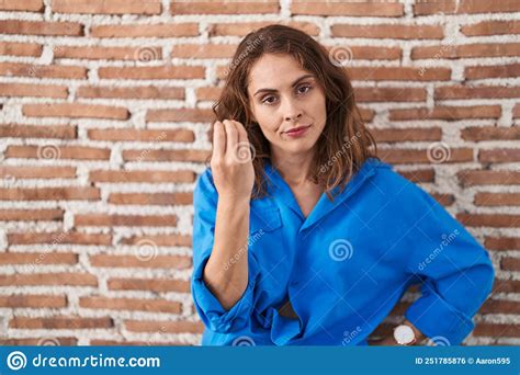 Beautiful Brunette Woman Standing Over Bricks Wall Doing Italian Gesture With Hand And Fingers