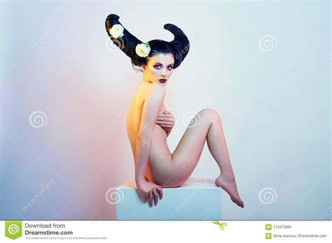 Art Fashion Nude Girl With Hair Horns Sitting On A White Cube B Stock