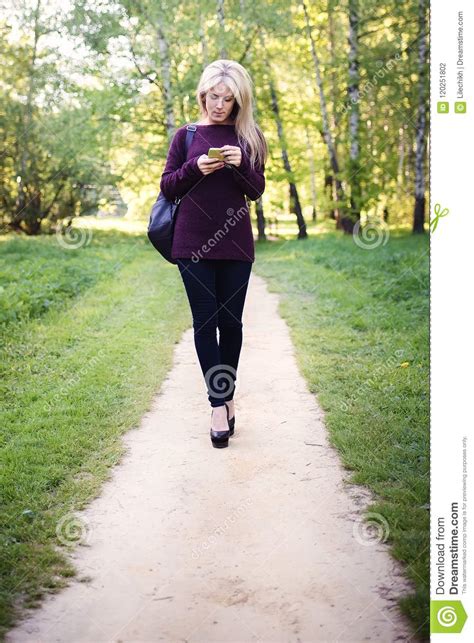 A Girl With Blond Hair Walks In The Park On A Sunny Spring Day Stock