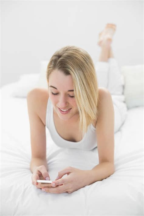 Attractive Calm Woman Texting With Her Smartphone Lying On Her B Stock Image Image Of Indoors