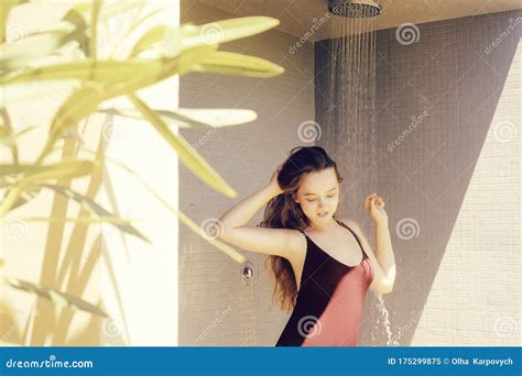 a girl takes a shower in the street in a public shower a girl with long hair in a red one piece