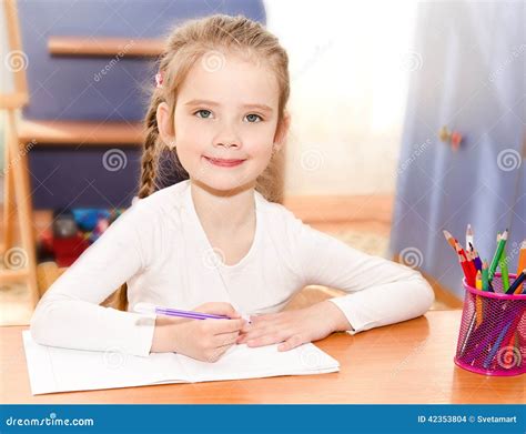 Cute Smiling Little Girl Is Writing At The Desk Stock Photo Image Of