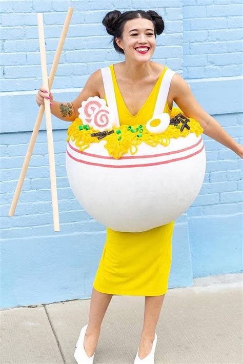 a woman in a yellow dress holding two sticks and a large white bowl with flowers on it