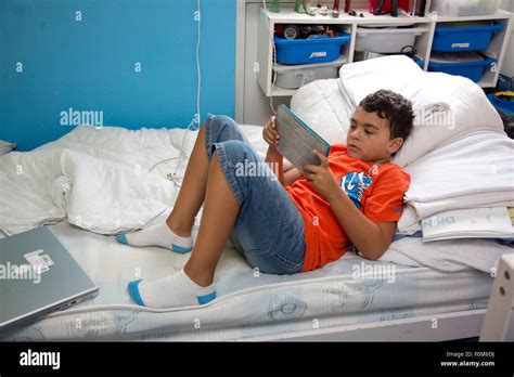 Young Boy Lying On His Bed Looking At His Tablet Alone Stock Photo Alamy