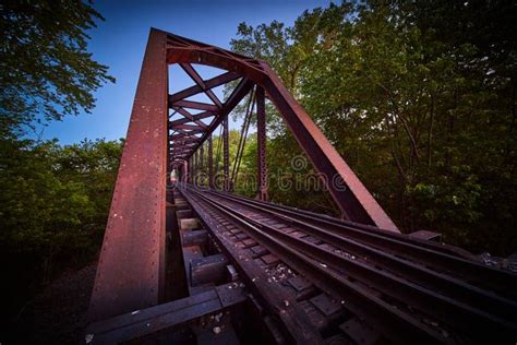Side View Of Purple Metal Bridge For Train Tracks In Forest Stock Photo