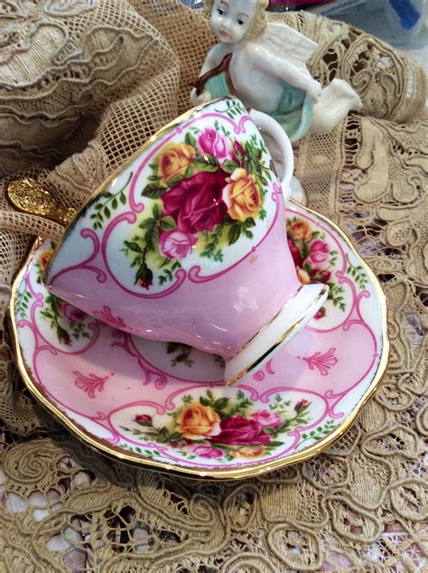 A Pink Tea Cup And Saucer Sitting On Top Of A Lace Doily Covered Table