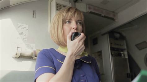 Blonde Stewardess Speaks To The Loadspeaker In The Cabin Of Airplane