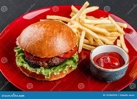 Beef Burger And French Fries With Tomato Sauce On Red Plate Over Dark