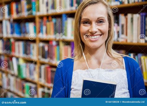 Smiling Female Student Listening To Music In The Library Stock Photo