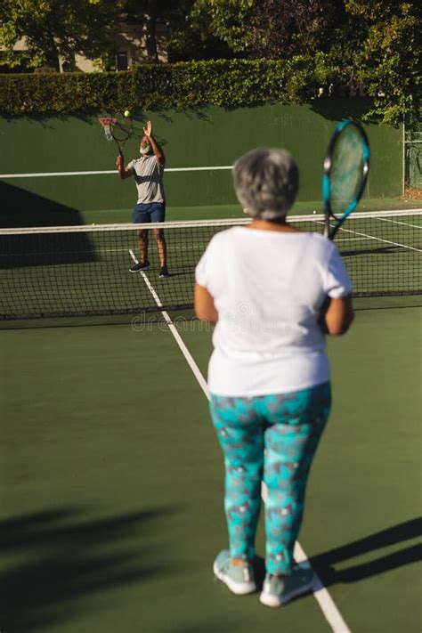 Senior African American Couple Playing Tennis On Tennis Court Stock
