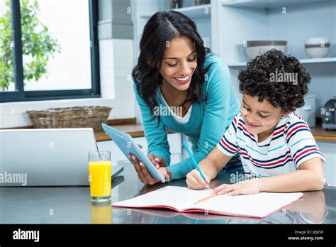 Kind Mother Helping Her Son Doing Homework In Kitchen Stock Photo Alamy