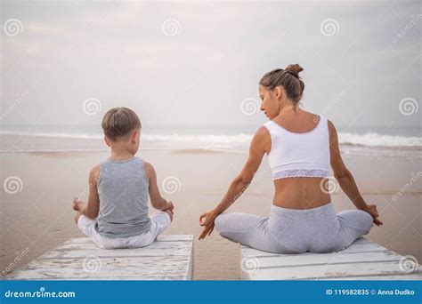 A Mother And A Son Are Doing Yoga Exercises At The Seashore Of T Stock