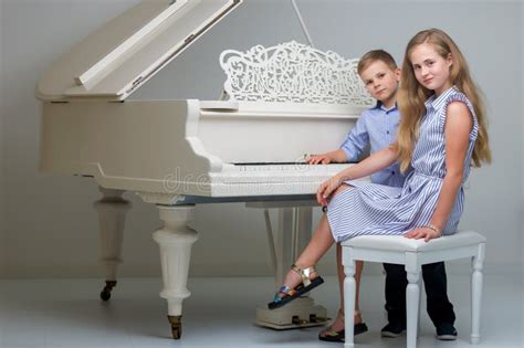 Two Little Kids Girl And Boy Playing Piano In Living Room Or Mus Stock