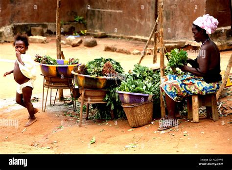 Horizontal Environmental Portrait Of Old Woman At Vegetable Stall In