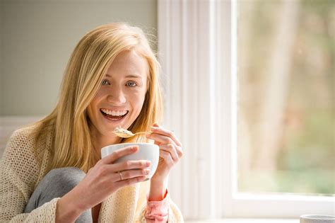 Blonde Woman Smiling And Eating Breakfast By The Window Editorial