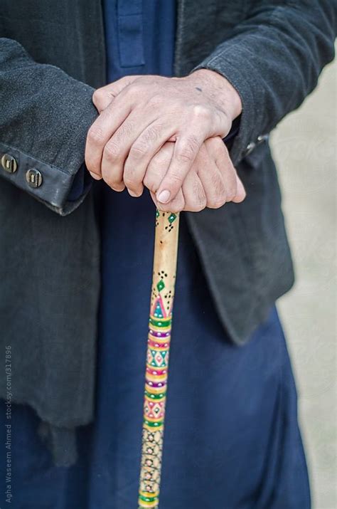 An Older Person Holding A Wooden Stick With Designs On Its Handle And