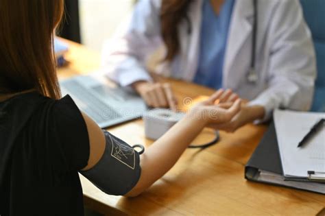 Cropped Image Of Nurse Measuring Blood Pressure Female Patient At Table