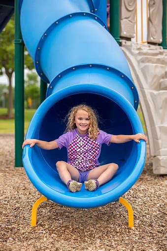 Girl At Bottom Of Blue Tube Slide At Playground Stock Photo Download